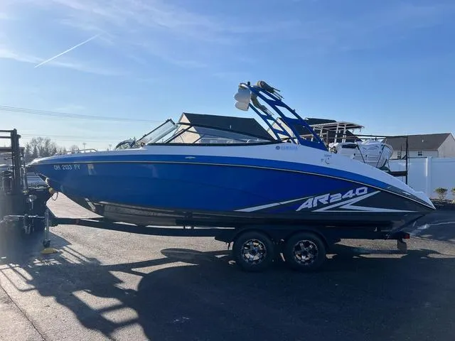 Slide: The Image of 2020 Yamaha AR240 boat in blue on a trailer, parked outdoors. - 1