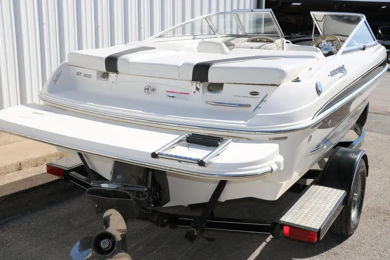 Slide: The Image of 2009 Glastron GT185 boat on trailer, rear view, white exterior, parked near building. - 4