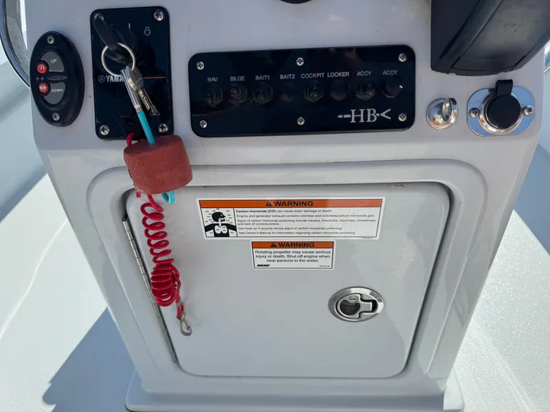 Slide: The Image of 2023 Hell's Bay Professional boat console with controls, key, and warning labels. - 11