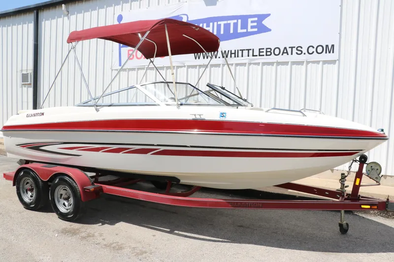 Slide: The Image of 2007 Glastron GT205 boat with red accents on a trailer, parked outside a building. - 11