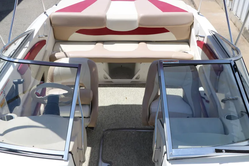 Slide: The Image of 2007 Glastron GT205 boat interior with beige and red seating, dual windshields, and steering wheel. - 21