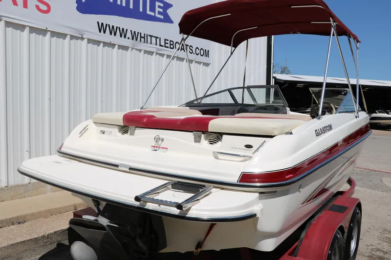 Slide: The Image of 2007 Glastron GT205 boat with red canopy on trailer, parked near Whittle Boats sign. - 4