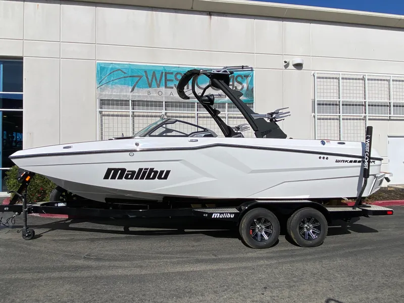 Slide: The Image of 2025 Malibu Wakesetter 22 MXZ boat on trailer outside dealership. - 1