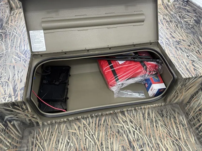 Slide: The Image of 2025 Tracker Grizzly® 1650 T Prairie Wings Edition storage compartment with safety gear and accessories. - 7