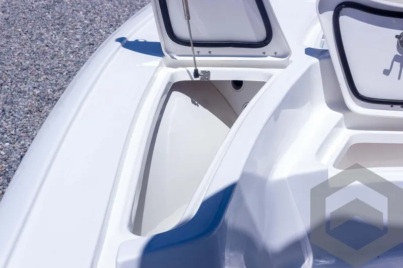 Slide: The Image of 2025 Tidewater 2410 Bay Max boat storage compartment, open lid, white interior, gravel background. - 21