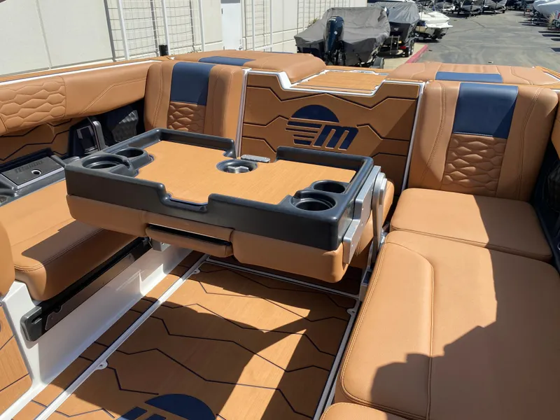 Slide: The Image of 2025 Malibu Wakesetter 24 MXZ interior with tan and blue seating, featuring a foldable table. - 14