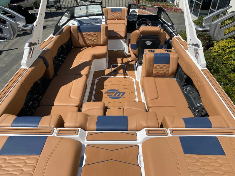 Slide: The Image of 2025 Malibu Wakesetter 24 MXZ interior with tan and blue seating, luxury design. - 8