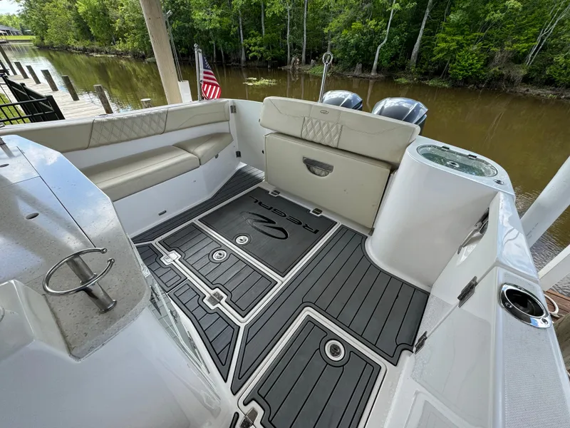 Slide: The Image of 2019 Regal 33 SAV boat interior with seating and American flag, docked by a river. - 18