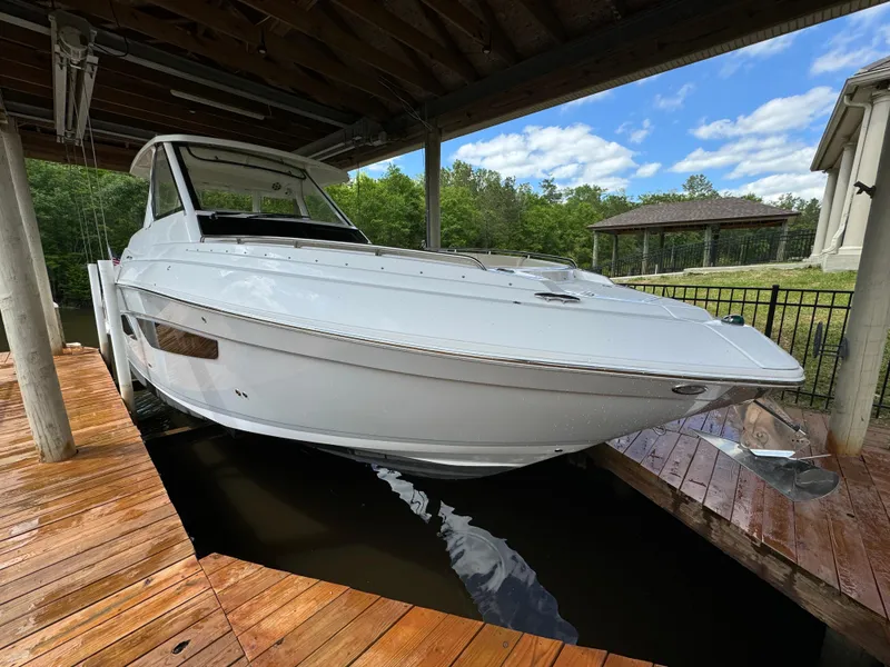 Slide: The Image of 2019 Regal 33 SAV boat docked under wooden shelter, surrounded by lush greenery. - 2