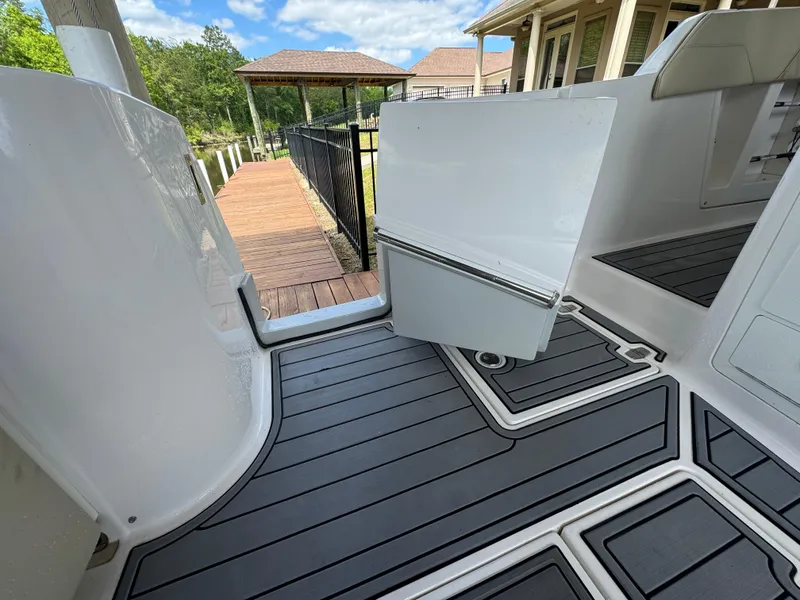 Slide: The Image of 2019 Regal 33 SAV boat deck with open hatch, near wooden dock and house. - 21