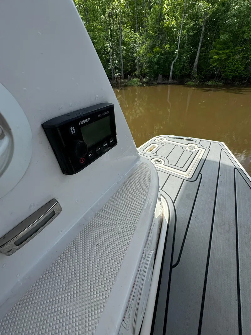 Slide: The Image of 2019 Regal 33 SAV boat with deck view, featuring a control panel, near a wooded riverbank. - 25