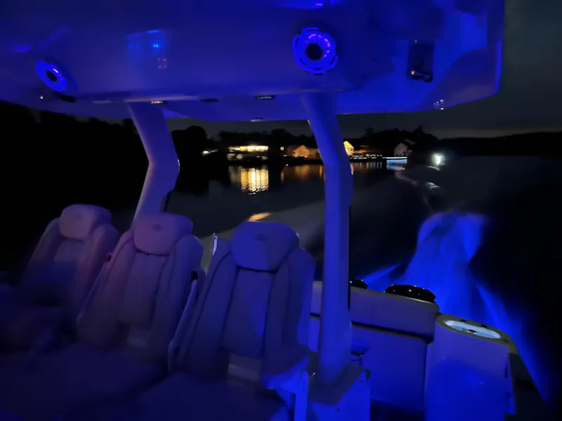 Slide: The Image of 2019 Regal 33 SAV boat interior with blue LED lighting at night on a calm lake. - 38