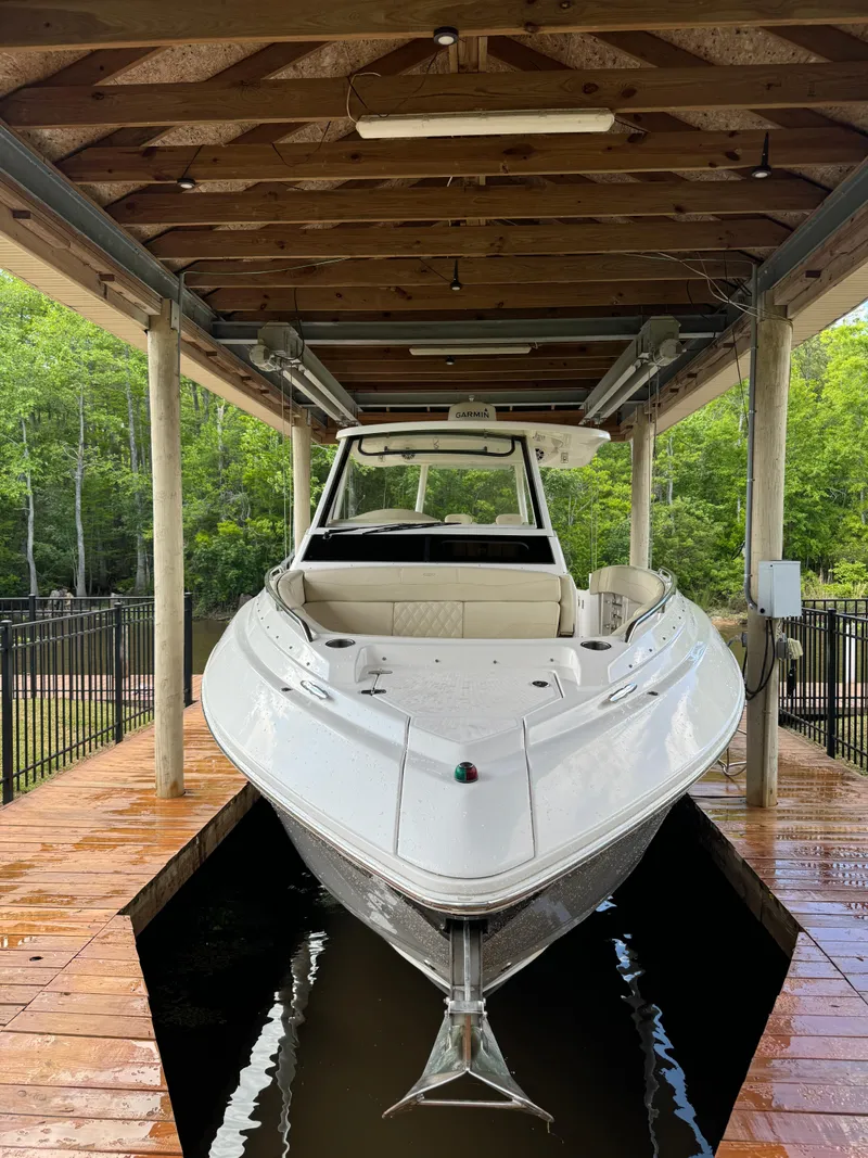 Slide: The Image of 2019 Regal 33 SAV boat docked under wooden shelter, surrounded by greenery. - 4