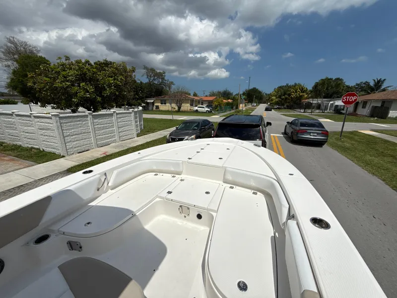 Slide: The Image of 2021 Robalo 246 Cayman SD boat on a residential street under a cloudy sky. - 14