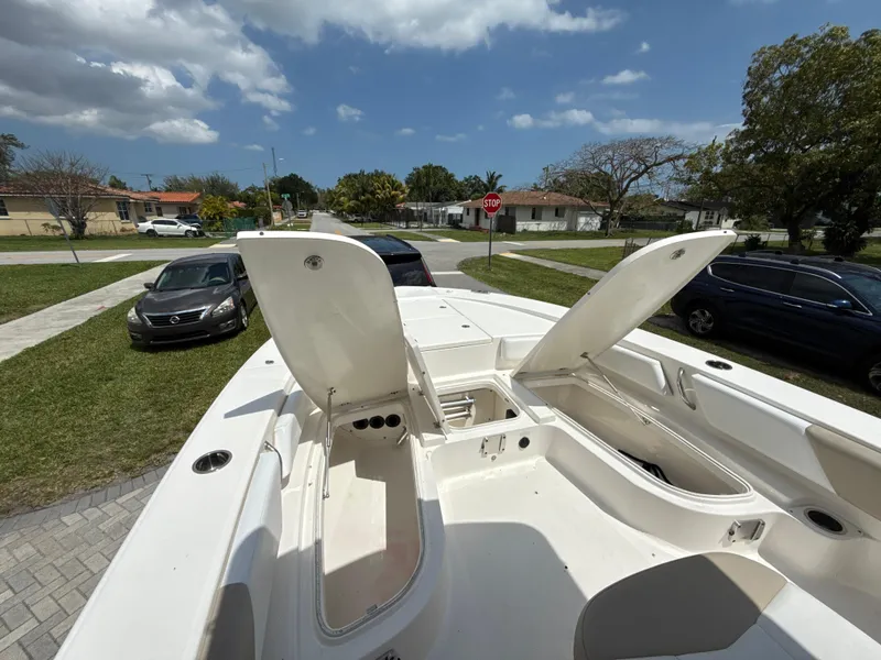 Slide: The Image of 2021 Robalo 246 Cayman SD boat with open storage compartments, parked in a suburban area. - 16