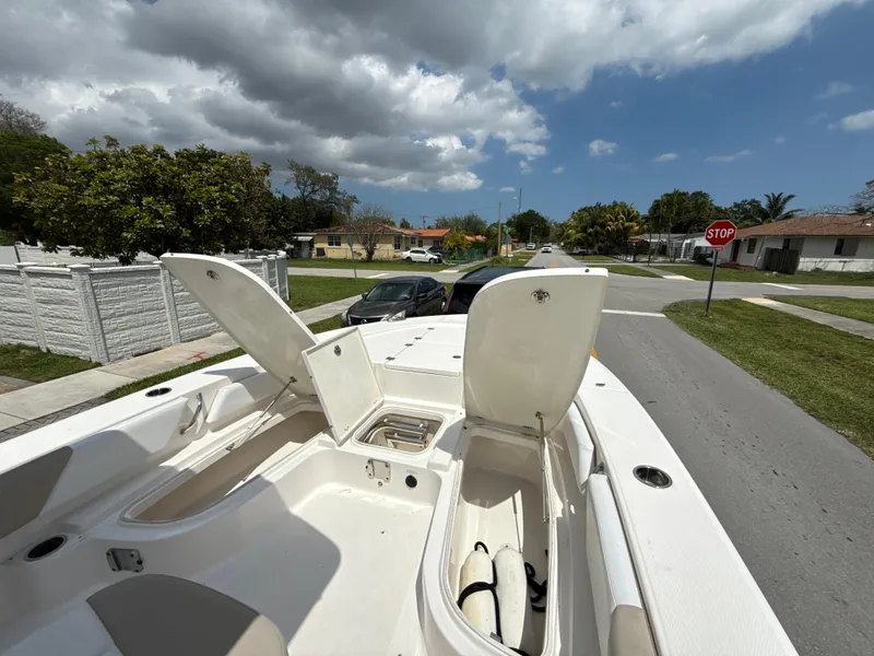 Slide: The Image of 2021 Robalo 246 Cayman SD boat with open storage compartments on a sunny street. - 17