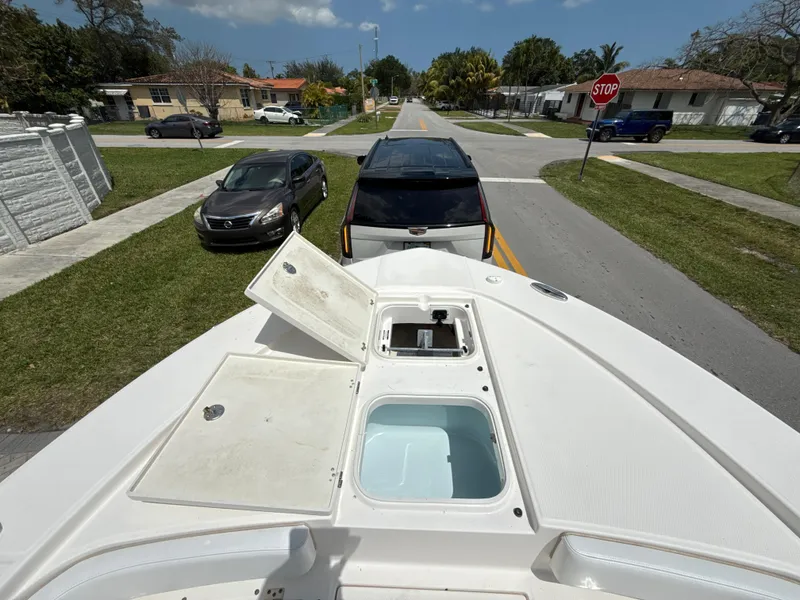 Slide: The Image of 2021 Robalo 246 Cayman SD boat with open storage compartments, parked on a residential street. - 18
