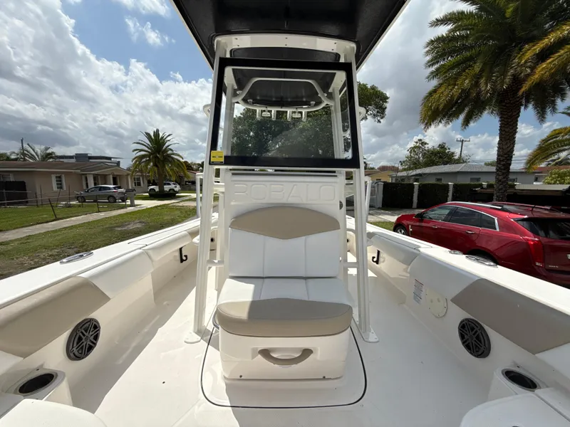 Slide: The Image of 2021 Robalo 246 Cayman SD boat interior with seating and console, parked in a residential area. - 20