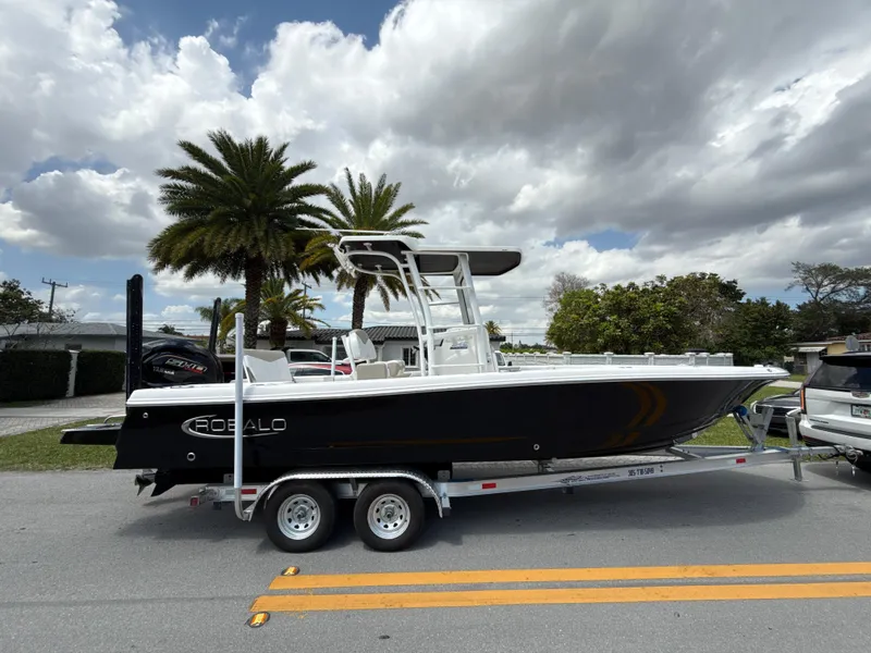 Slide: The Image of 2021 Robalo 246 Cayman SD boat on trailer, parked roadside under cloudy sky. - 3