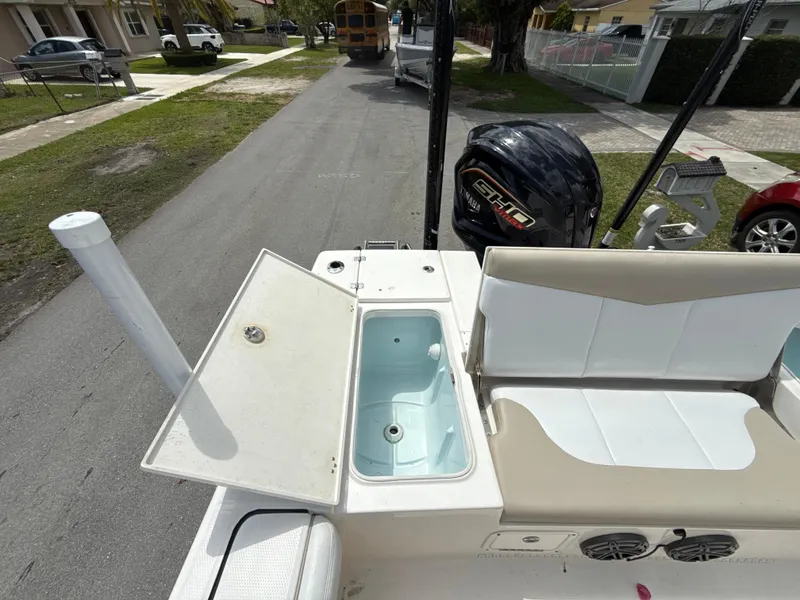 Slide: The Image of 2021 Robalo 246 Cayman SD boat with open storage compartment and seating, parked on a residential street. - 9