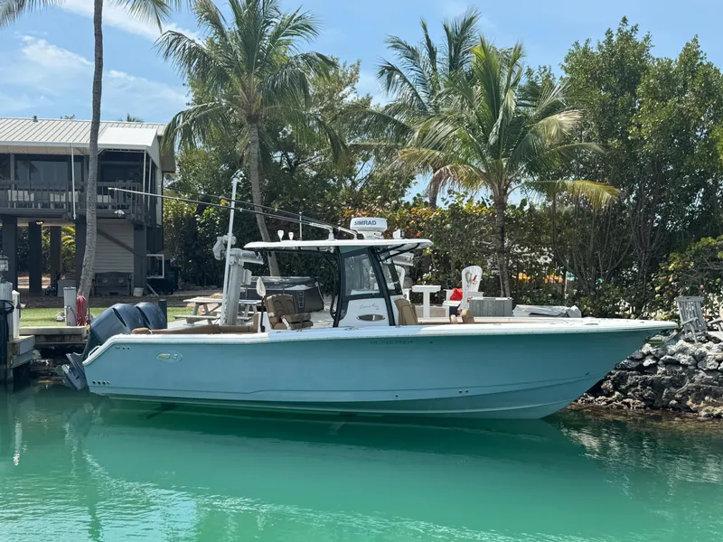 Slide: The Image of 2020 Sea Hunt Gamefish 30 boat docked, surrounded by palm trees and clear water. - 13