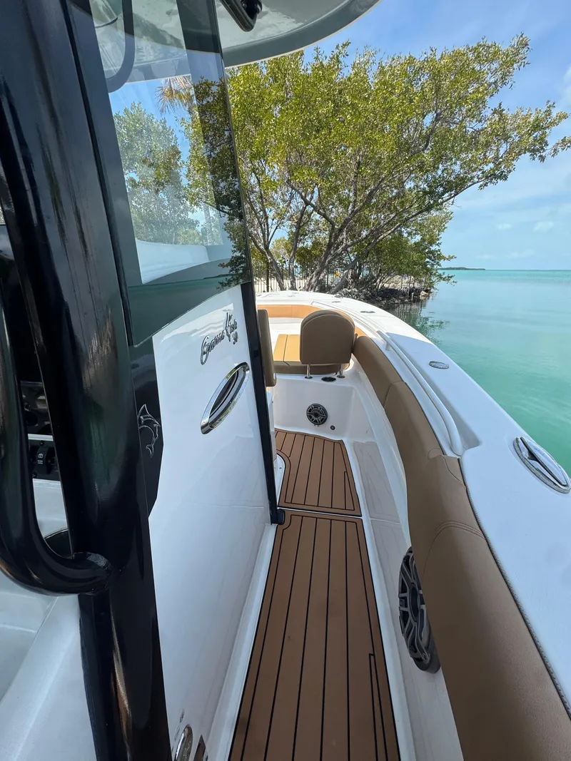 Slide: The Image of 2020 Sea Hunt Gamefish 30 boat with forward seating, docked near clear water and trees. - 17