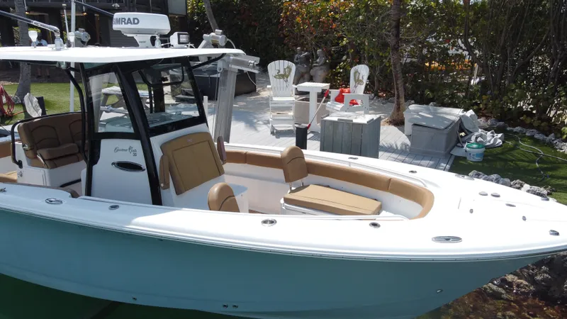 Slide: The Image of 2020 Sea Hunt Gamefish 30 boat with forward seating, docked near a garden area. - 5