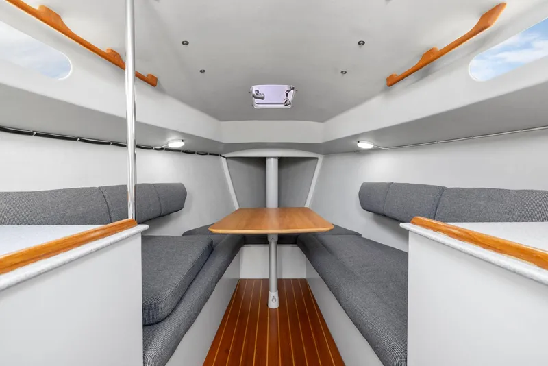 Slide: The Image of 2004 Wyliecat 30 sailboat interior with wooden table, gray seating, and sleek design. - 19