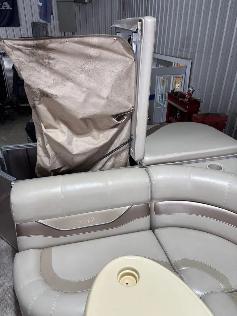 Slide: The Image of 2011 Avalon LS 23' RE boat interior with beige seating and table in a garage setting. - 11