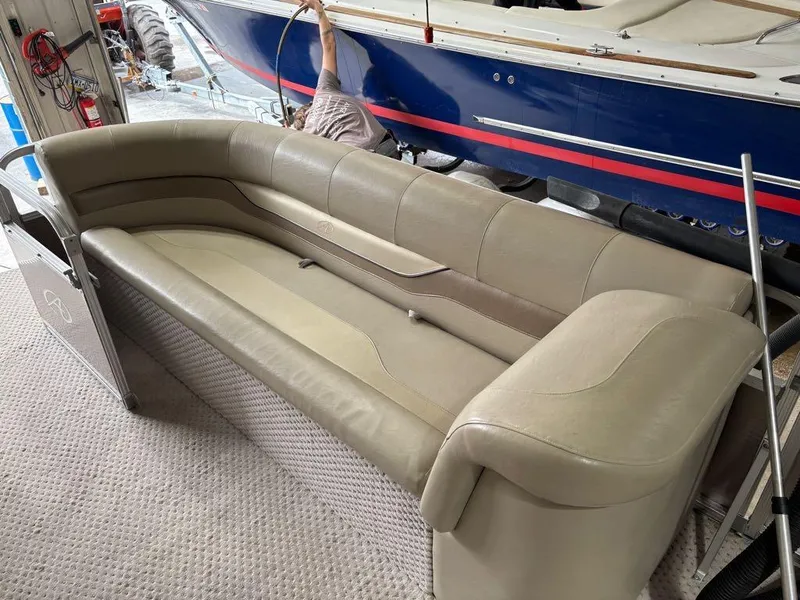 Slide: The Image of 2011 Avalon LS 23' RE boat interior with beige seating, in a garage setting. - 4
