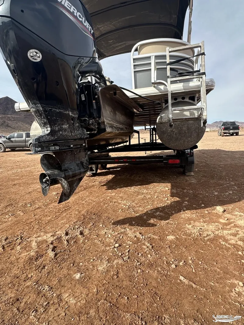 Slide: The Image of 2020 Tracker Party Barge 24 DLX on trailer, desert landscape background. - 12