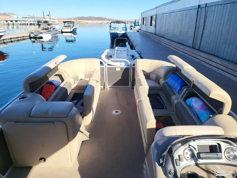 Slide: The Image of 2020 Tracker Party Barge 24 DLX pontoon boat with spacious seating at a marina. - 6
