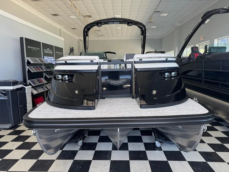 Slide: The Image of 2025 Bennington 25QFBA pontoon boat displayed in showroom with checkered floor. - 2