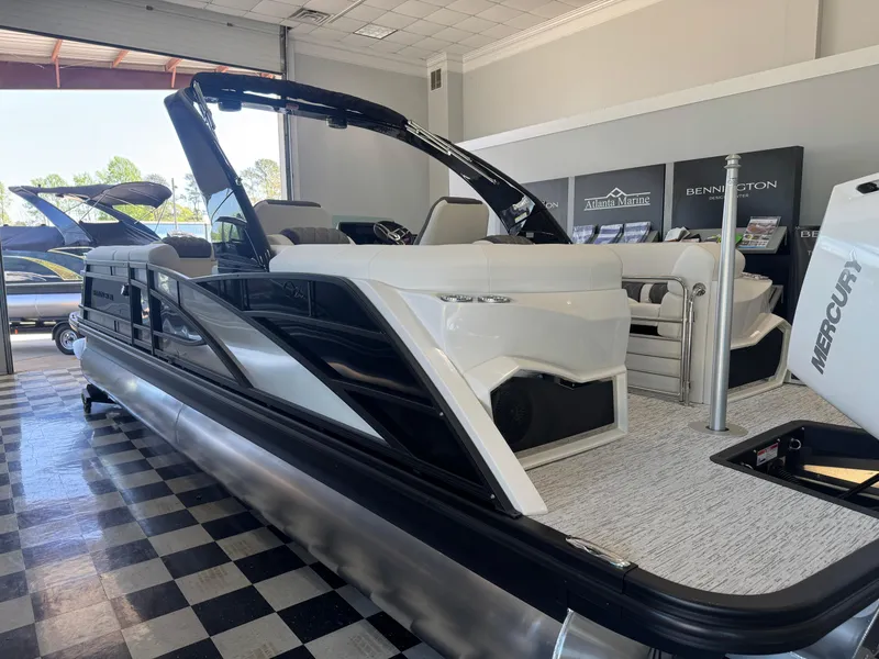 Slide: The Image of 2025 Bennington 25QFBA pontoon boat displayed indoors with Mercury engine. - 7