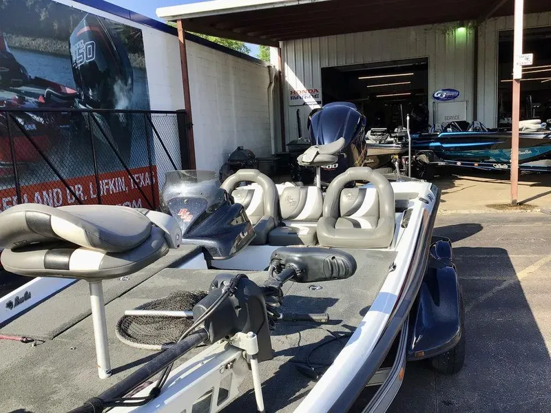 Slide: The Image of 2018 Bass Cat Panterra II boat with seating and motor, parked outside a marine service shop. - 28