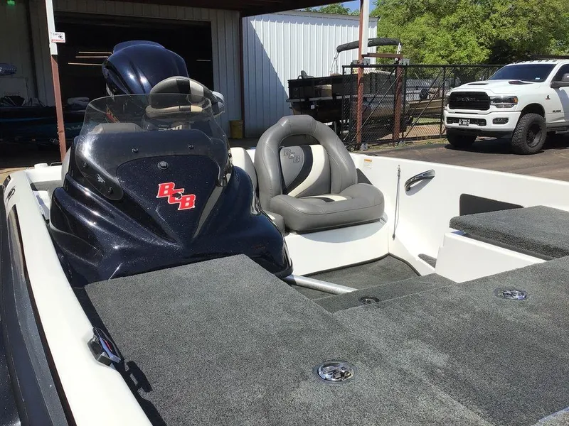 Slide: The Image of 2018 Bass Cat Panterra II boat interior with seating and dashboard, parked outdoors. - 42