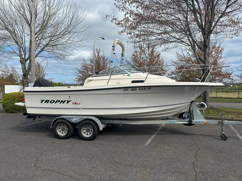 Slide: The Image of 2002 Trophy Pro boat on trailer in parking lot, overcast sky, bare trees. - 0