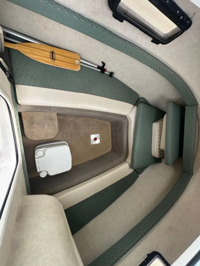 Slide: The Image of 2002 Trophy boat interior with green upholstery, paddle, and portable toilet. - 14