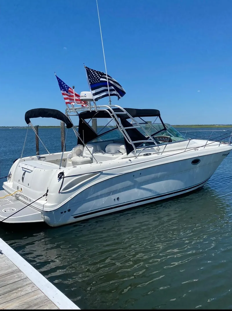 Slide: The Image of 2005 Sea Ray 290 Amberjack boat docked with flags, under clear blue sky. - 2