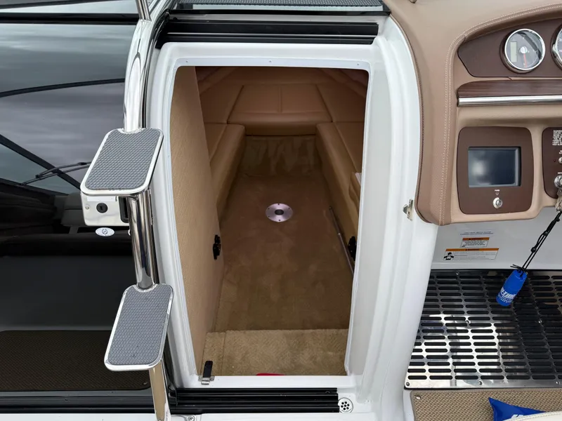 Slide: The Image of 2013 Cobalt 273 boat interior cabin with beige seating and dashboard controls. - 14