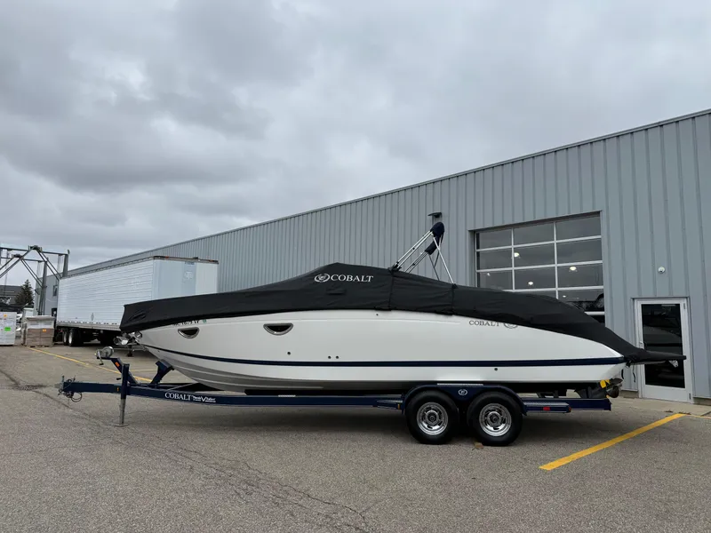 Slide: The Image of 2013 Cobalt 273 boat with cover on trailer, parked outside industrial building. - 24