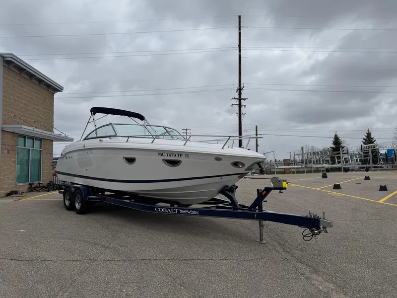 Slide: The Image of 2013 Cobalt 273 boat on trailer in parking lot under cloudy sky. - 6