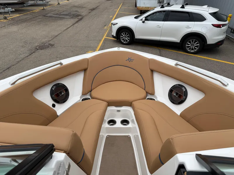 Slide: The Image of 2018 MasterCraft XT23 boat interior with tan seating and speakers, parked near a white SUV. - 17