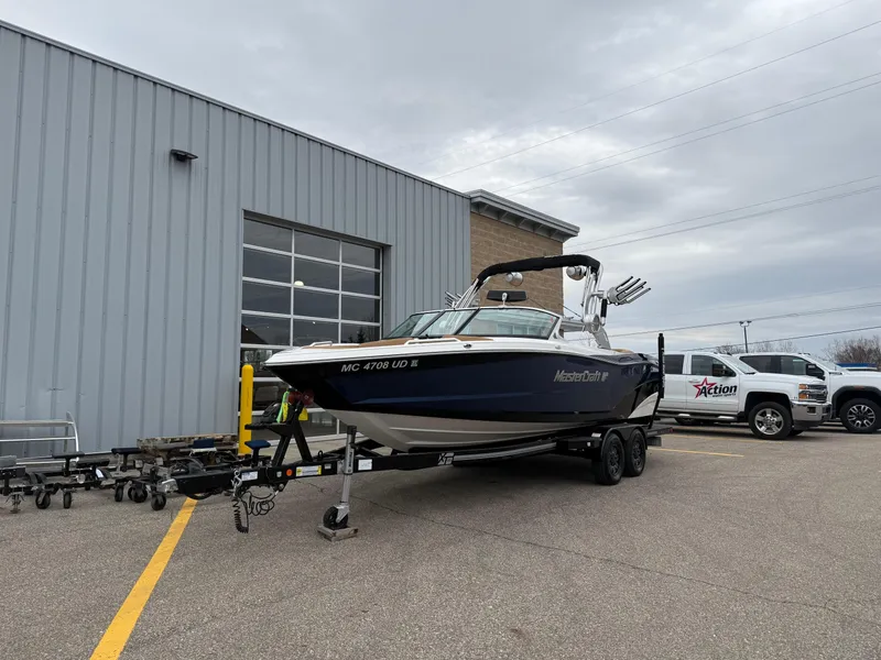 Slide: The Image of 2018 MasterCraft XT23 boat on trailer outside a building, overcast sky. - 2