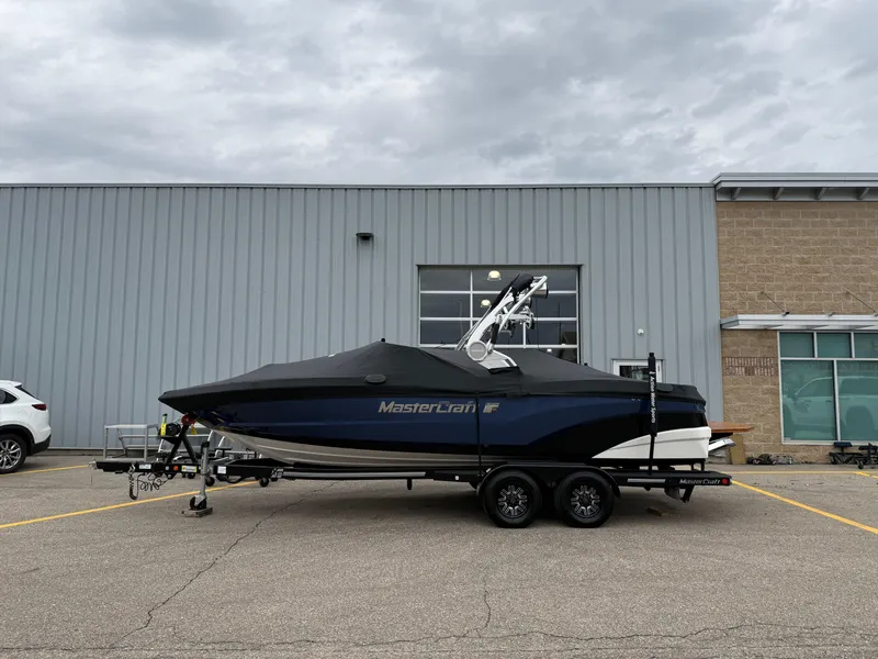 Slide: The Image of 2018 MasterCraft XT23 boat on trailer, parked outside industrial building. - 20