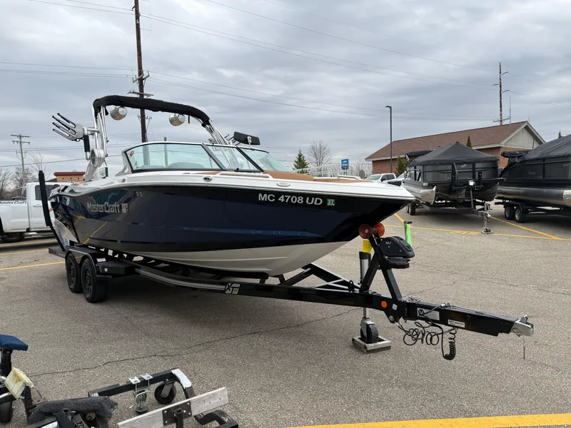 Slide: The Image of 2018 MasterCraft XT23 boat on trailer in parking lot, overcast sky. - 6