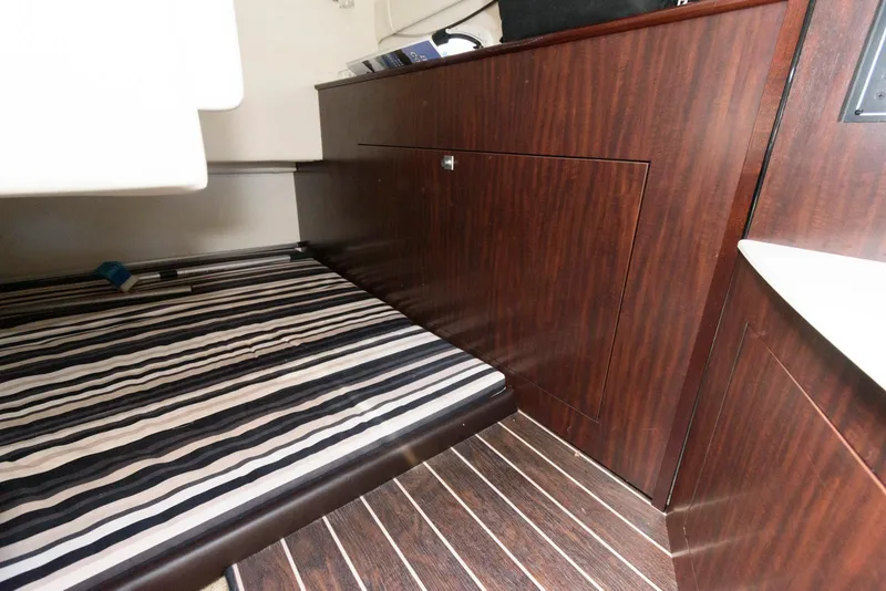 Slide: The Image of 2019 Monterey 295 Sport Yacht interior with striped bedding and wood cabinetry. - 13
