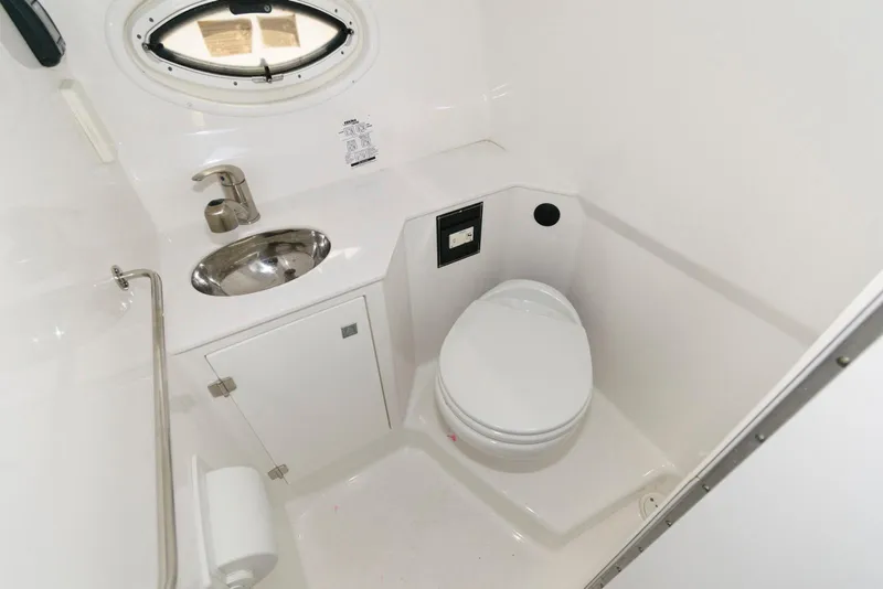 Slide: The Image of 2019 Monterey 295 Sport Yacht bathroom with sink, toilet, and porthole window. - 15