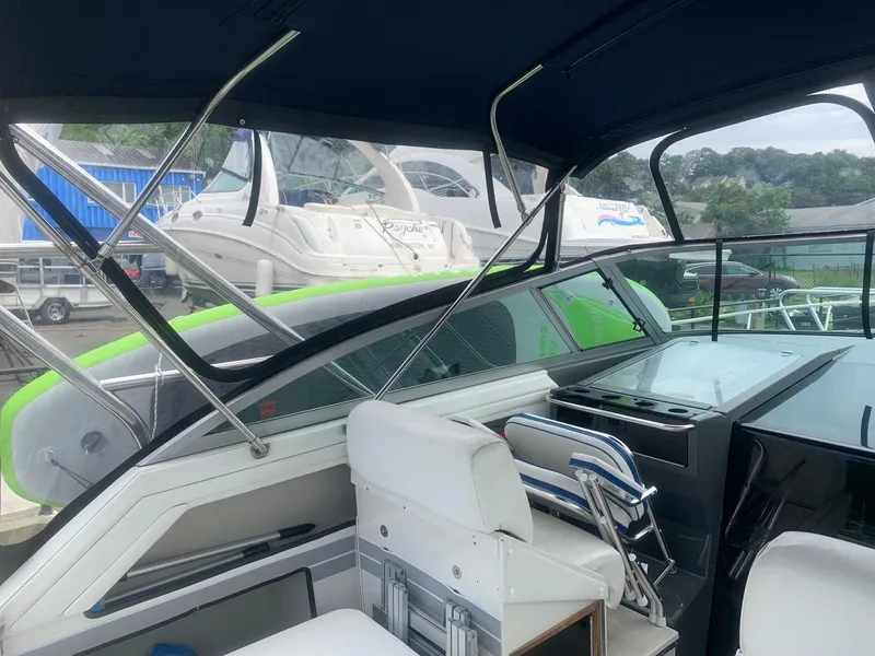 Slide: The Image of 1989 Cruisers Yachts 3670 Esprit interior with seating and dashboard, docked near other boats. - 5