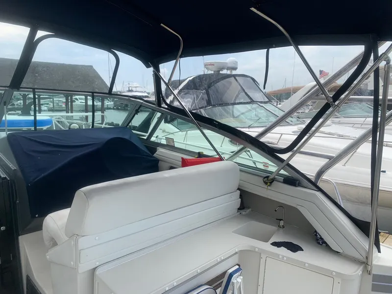 Slide: The Image of 1989 Cruisers Yachts 3670 Esprit interior with white seating and canopy, docked at marina. - 4